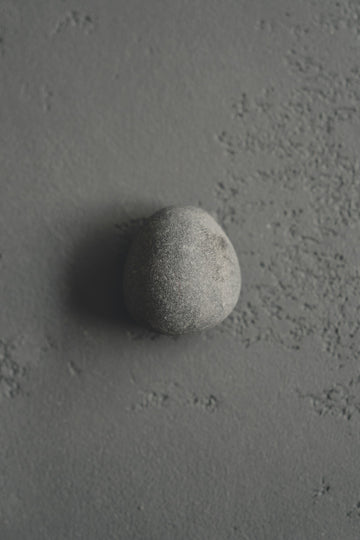 A single grey stone on a soft textured background — a calm starting point.